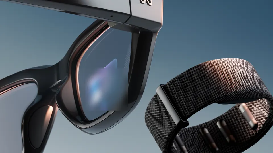Close-up of everyday-eyewear smart glasses with a small heads-up display card lit inside the right lens, and a fabric wristband beside them